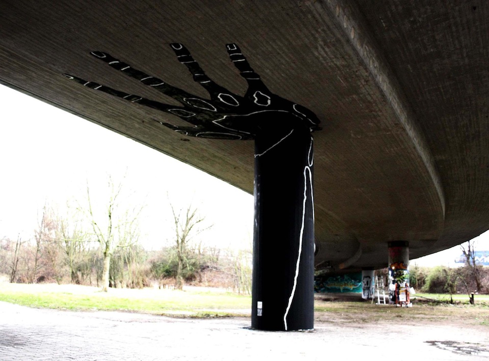 Pillar under a bridge painted as a giant hand, visually suggesting the hand is supporting the bridge.