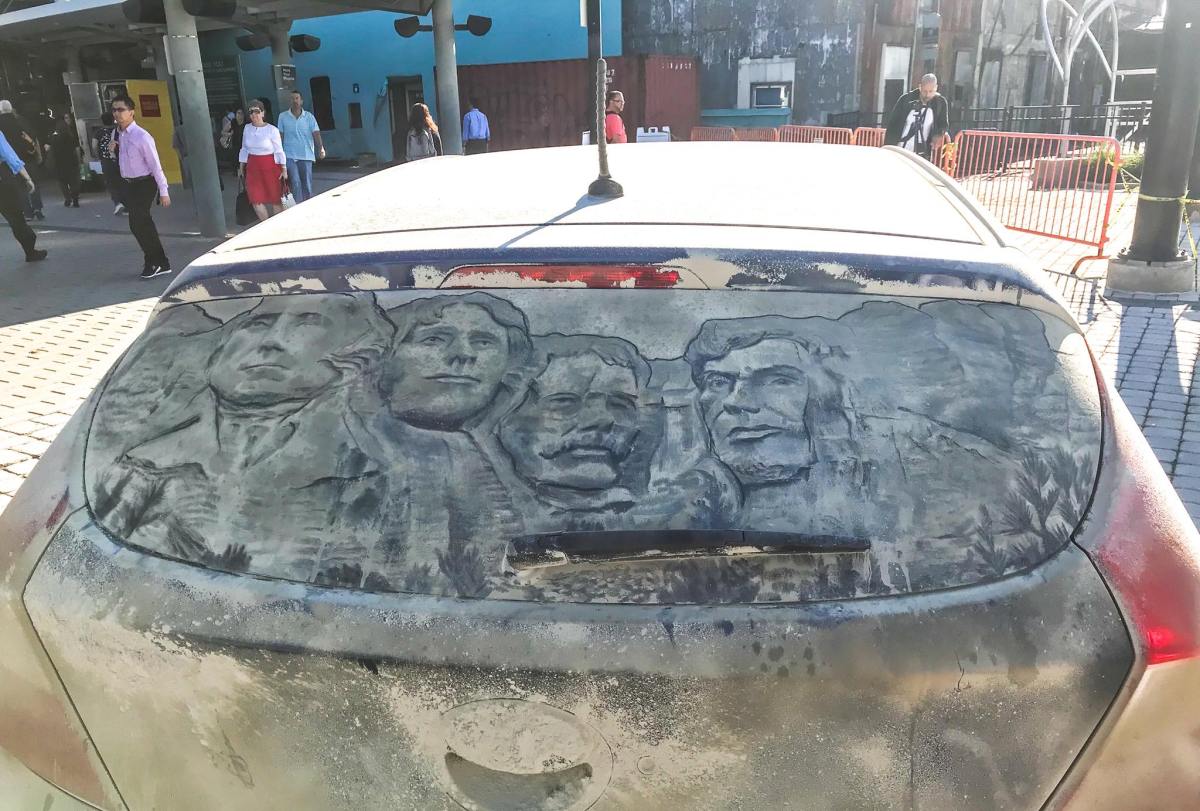 Mount Rushmore presidents drawn into the dust on a car window