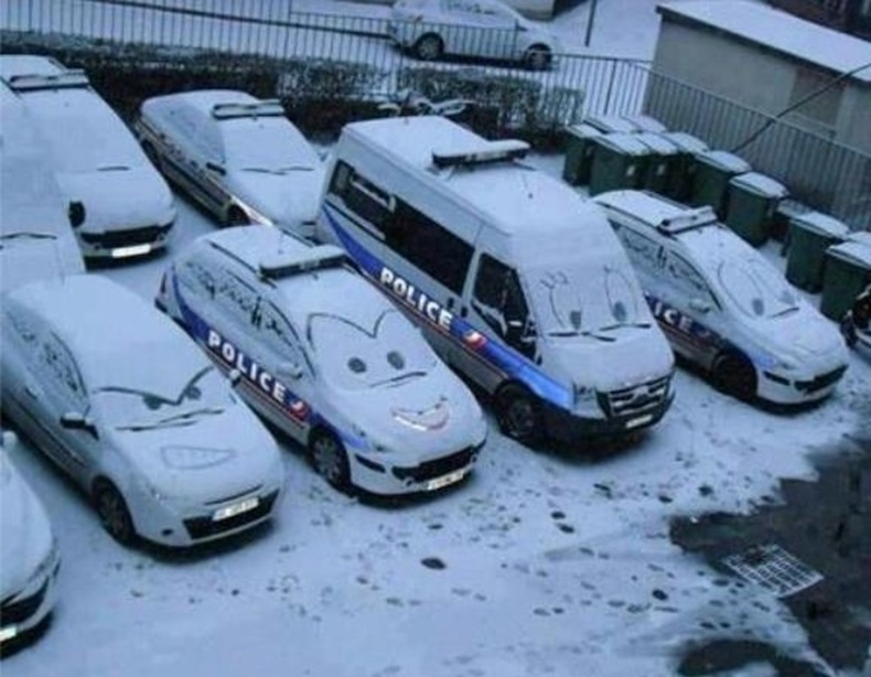 Faces drawn on snow-covered police cars