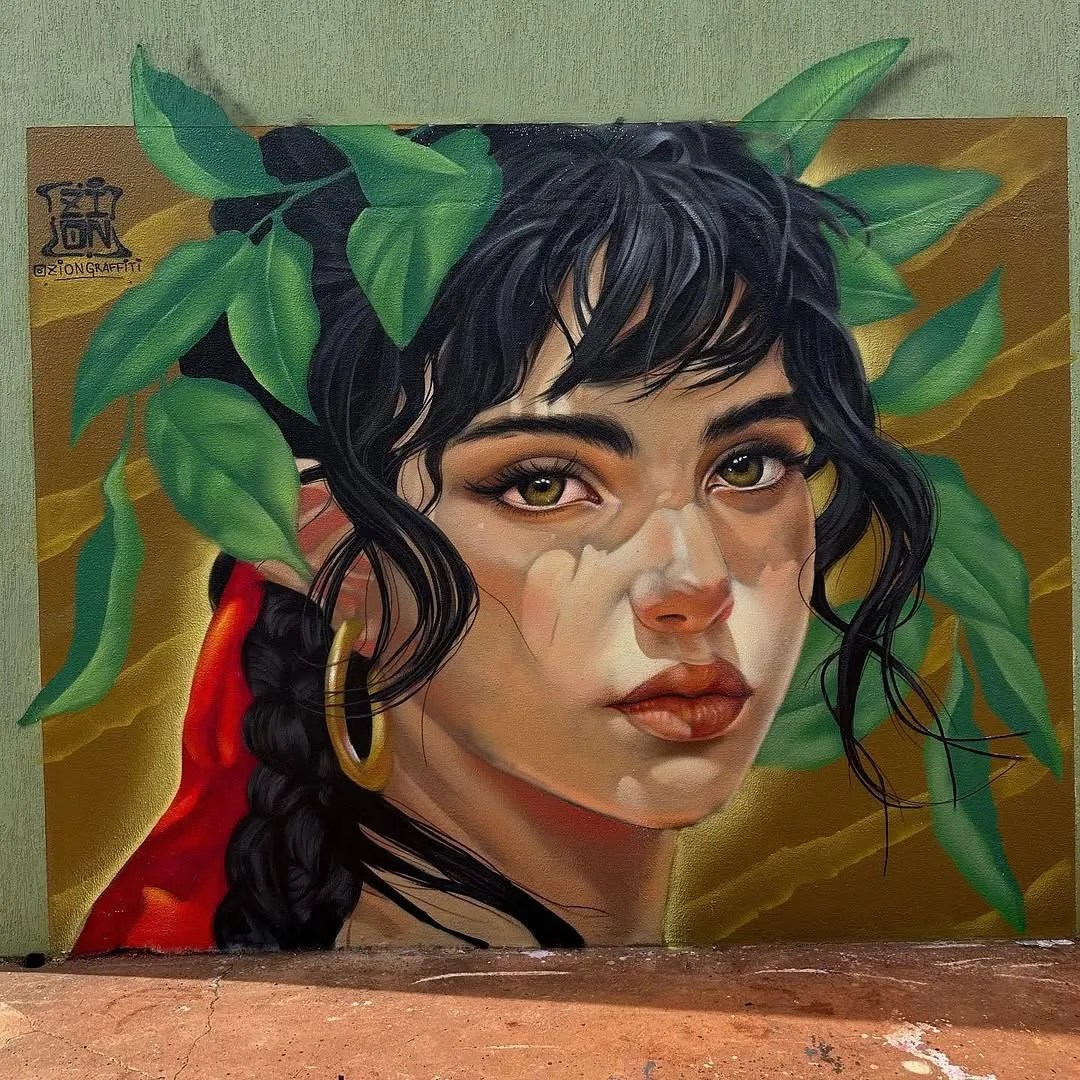 Mural by Zion Graffiti in Apucarana, Brazil featuring a realistic portrait of a woman with dark hair, gold hoop earrings, and green leaves framing her face, painted on a gold and green wall with soft shadowing.