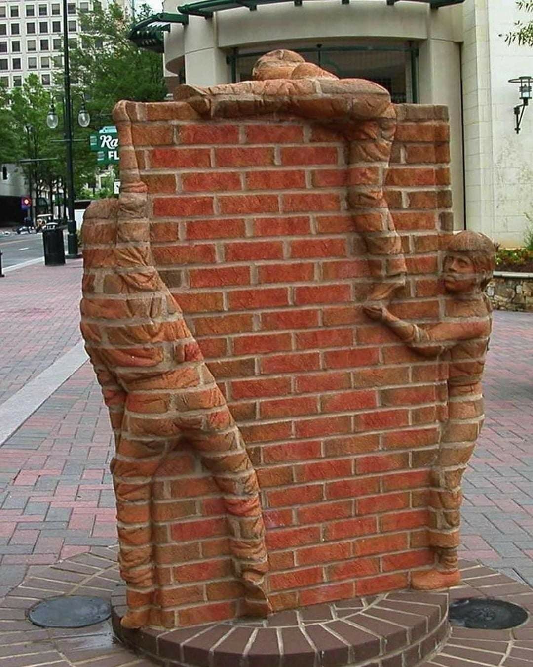 Brick sculpture by Brad Spencer in Charlotte, North Carolina, US, showing children climbing a red brick book-shaped wall, with their bodies sculpted directly from the same brick structure.
