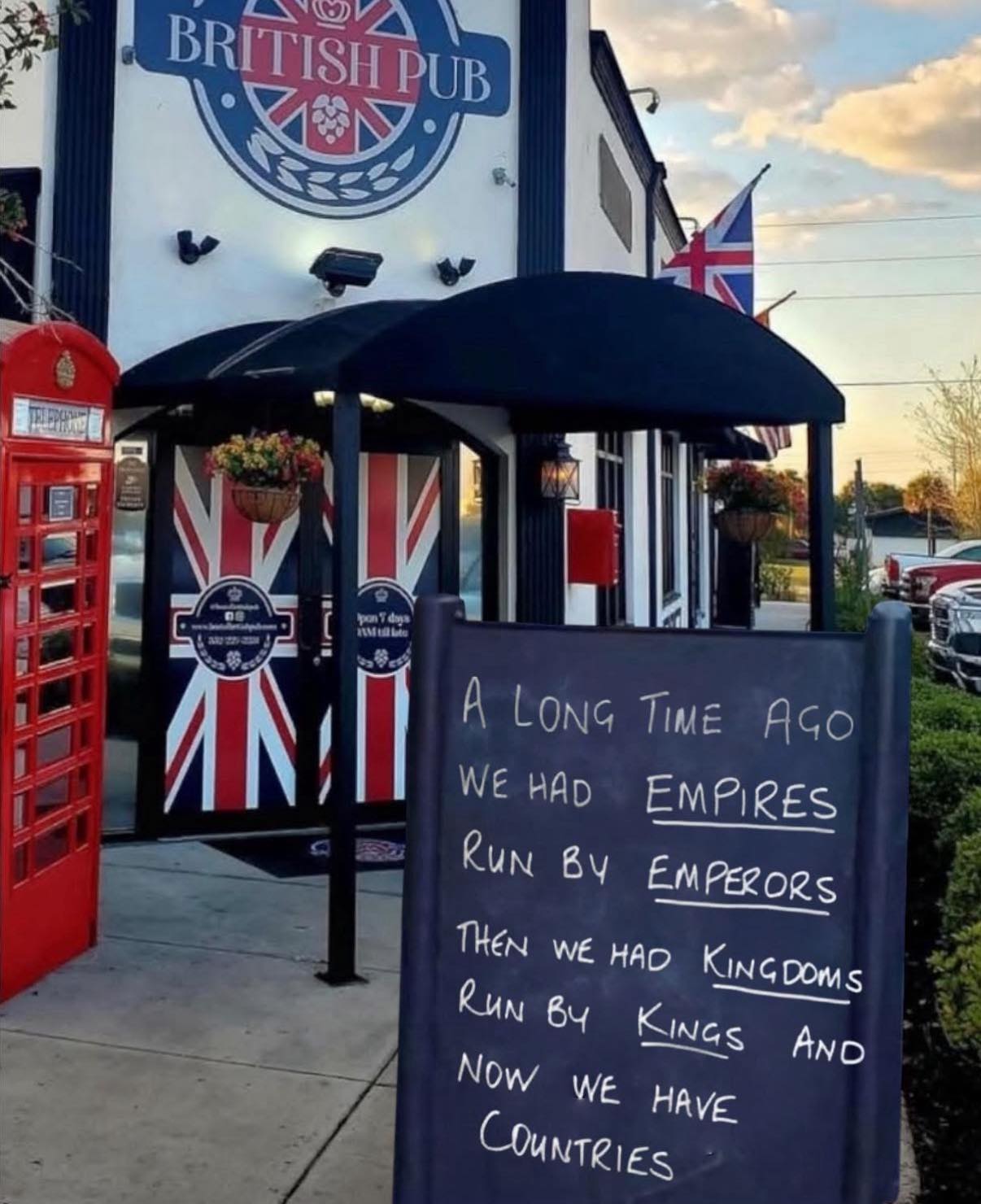 Sign outside a British pub humorously compares historical leadership: “Empires run by Emperors, Kingdoms run by Kings, now we have Countries.”
