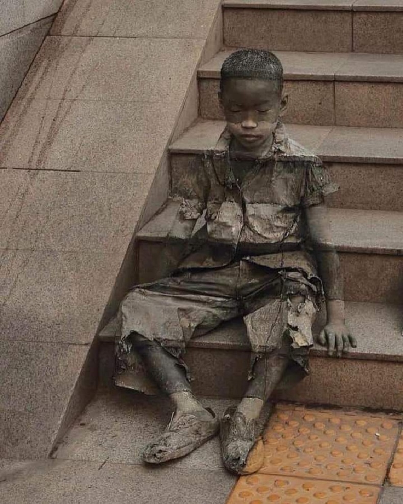 A young boy sits on a set of stone steps, painted to blend seamlessly into the background as part of UNICEF China’s 2008 “Invisibility of Poverty” campaign. His tattered clothing and closed eyes evoke a sense of vulnerability and solitude, symbolizing the often-overlooked struggles of homeless children. The artwork’s intricate camouflage highlights how poverty can render individuals invisible within urban settings, urging viewers to recognize and respond to their plight.