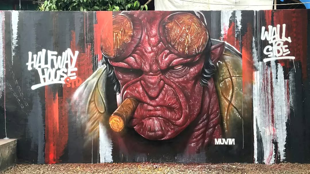 Mural of Hellboy with glowing goggles and a lit cigar, painted in red tones against a black and red striped graffiti wall, by Monkey D. Muvin in Tangerang, Indonesia.