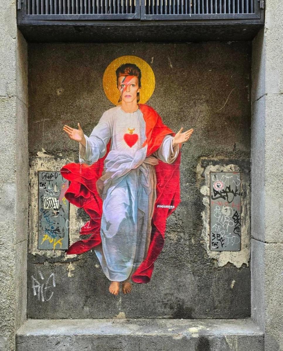Street art combining David Bowie’s Ziggy Stardust persona with a religious icon, including a halo, white robes, and sacred heart imagery, by FIGUE in Madrid, Spain.
