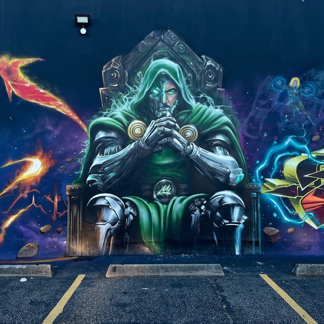A mural by Jay Mack in Passaic, New Jersey, depicting Doctor Doom seated on a throne, hands clasped in deep contemplation. His metallic armor gleams under a green cloak, with one glowing eye exuding an eerie power. The cosmic background bursts with vibrant energy, fiery meteors, and electrical currents, creating an epic, otherworldly atmosphere. A bold tribute to the iconic Marvel villain.