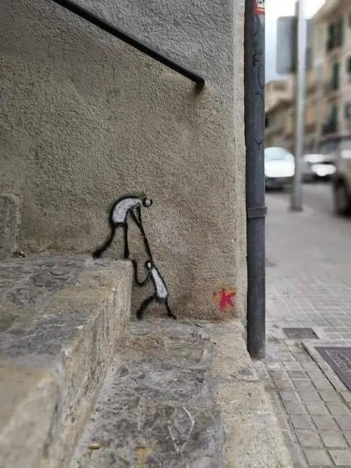 A minimalist line drawing on a building corner showing one stick figure leaning down to pull up another stick figure in Florence, Italy.