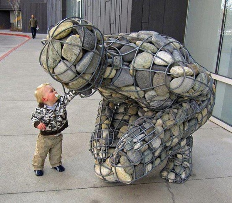 A child reaches out to touch The Weight of Grief sculpture.
