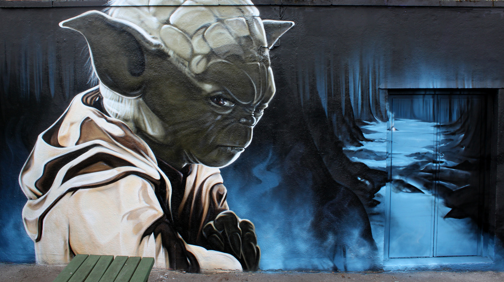 Yoda mural by SMUG, with Yoda in a robe facing a blue blast-like shape on a dark wall.