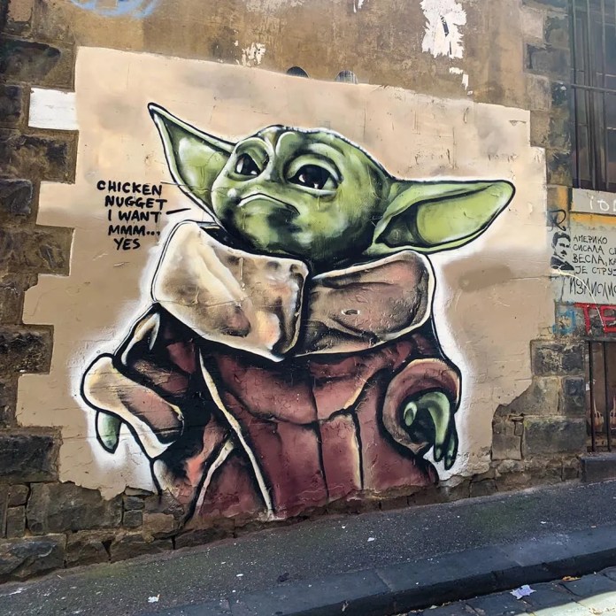 Baby Yoda street art by Lushsux on Higson Lane in Melbourne, Australia, painted on a weathered wall with a speech bubble reading “Chicken nugget I want mmm... yes.”