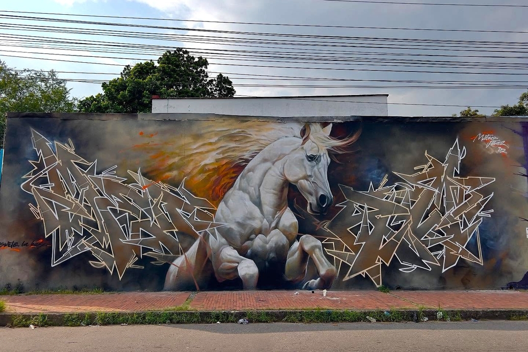 A mural featuring a powerful white horse in motion, its mane flowing against a stormy background, flanked by angular metallic graffiti lettering in silver and black. The piece exudes strength and dynamism.