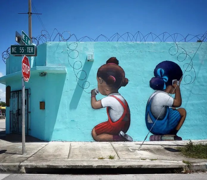 Seth's Little Haiti mural Telefòn in Miami, where two painted children use real barbed wire as a phone line.