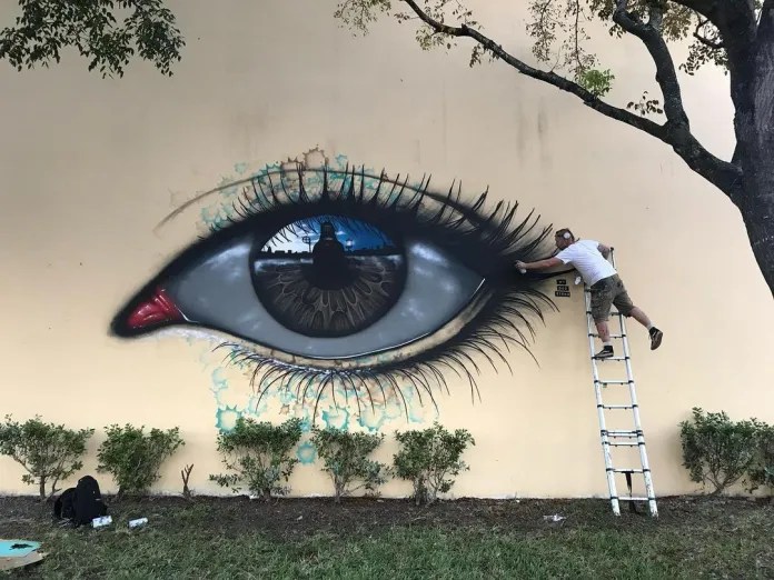 My Dog Sighs painting a large reflective eye mural in Miami for aWall Mural Projects.