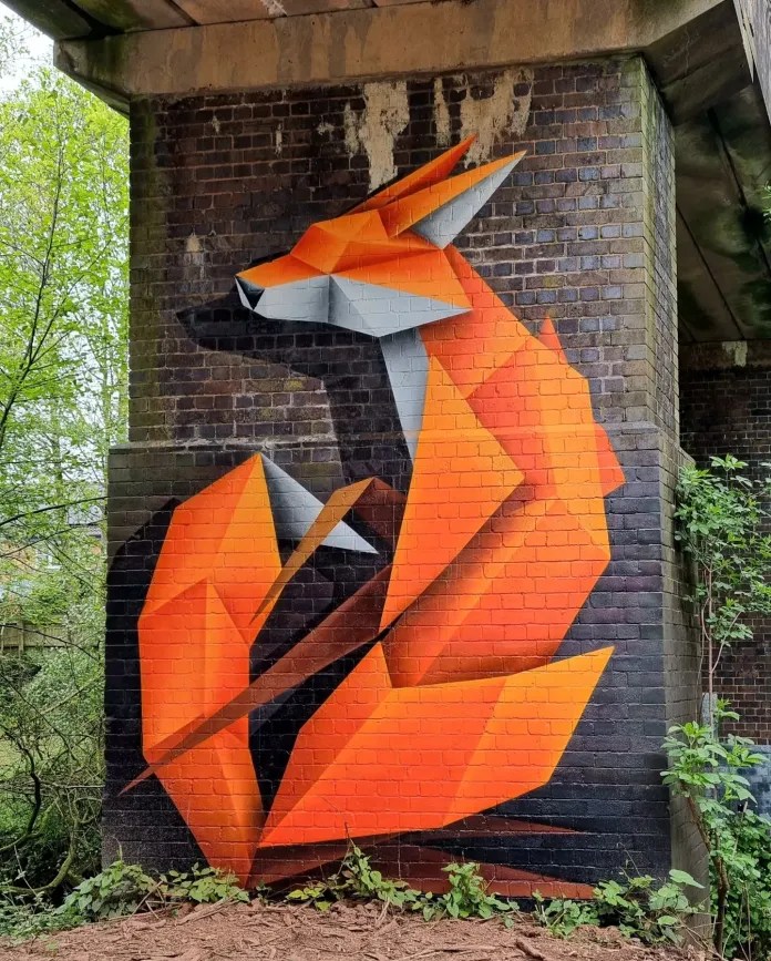 One of Annatomix's Longbridge Foxes in Birmingham, an orange origami-style fox painted beneath a bridge.