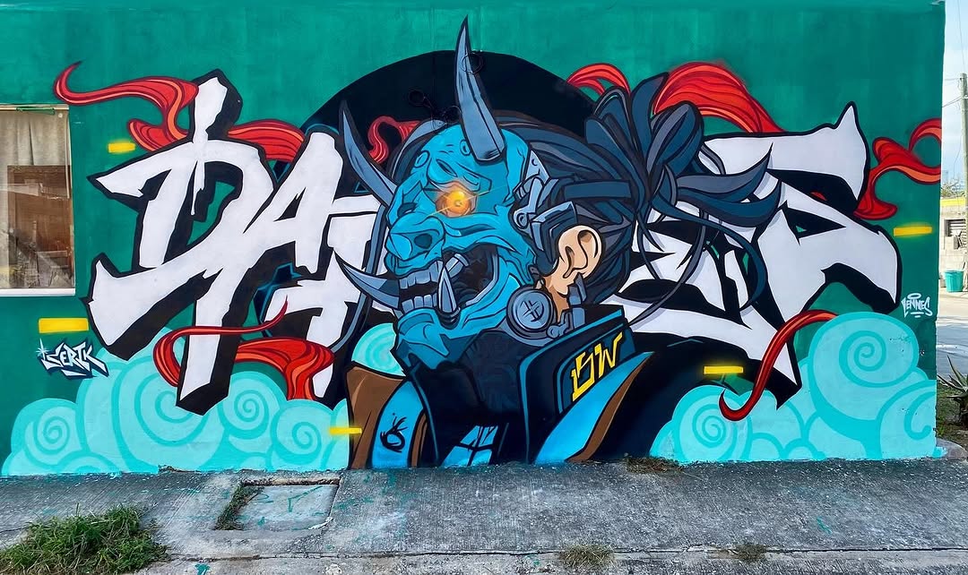Vibrant mural of a blue cyber-demon with robotic armor, horns, and a glowing eye, integrated with graffiti-style lettering and swirling red and aqua background elements.