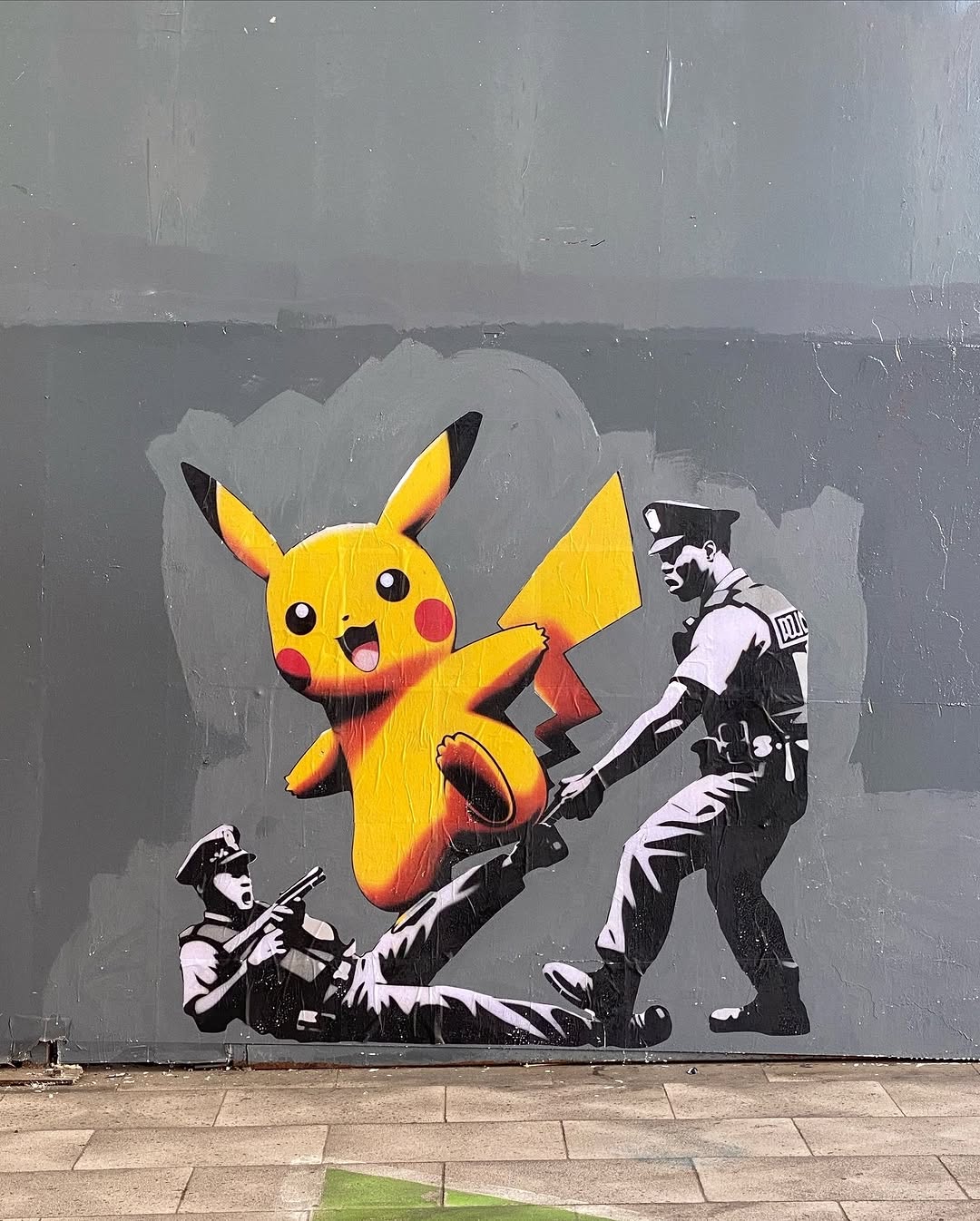 Street art showing Pikachu jumping joyfully in front of two riot police struggling on the ground, painted in black, grey, and bright yellow on a city wall in Santiago, Chile.