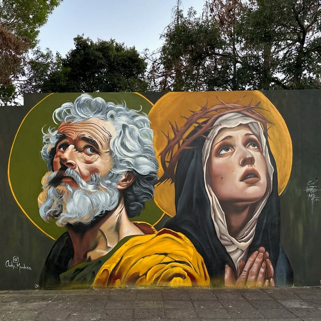 Mural by Chucky Alfredo Mendoza in Morelia, Mexico, showing a bearded man and a praying woman with halos, painted in a classical style with dramatic lighting and fine detail.