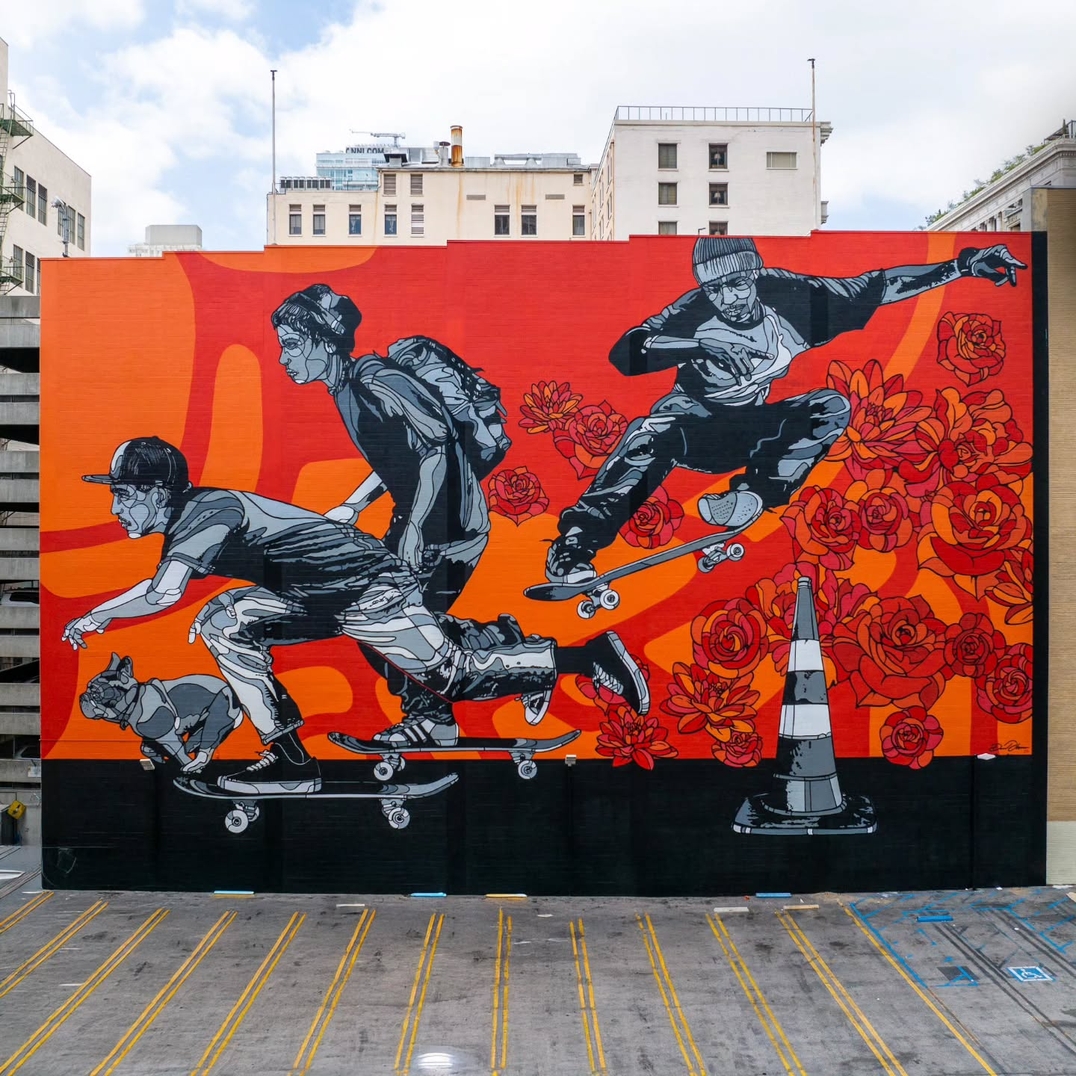 Mural by David Flores in Los Angeles, California, showing three grayscale skateboarders and a running cat against a red and orange wall filled with roses, set above a parking lot.