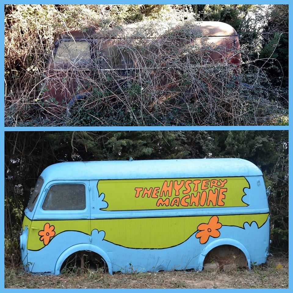 An old overgrown van painted by Oakoak as Scooby-Doo’s Mystery Machine, with blue and green panels, orange flower shapes, and vines hanging over the roof and windshield.