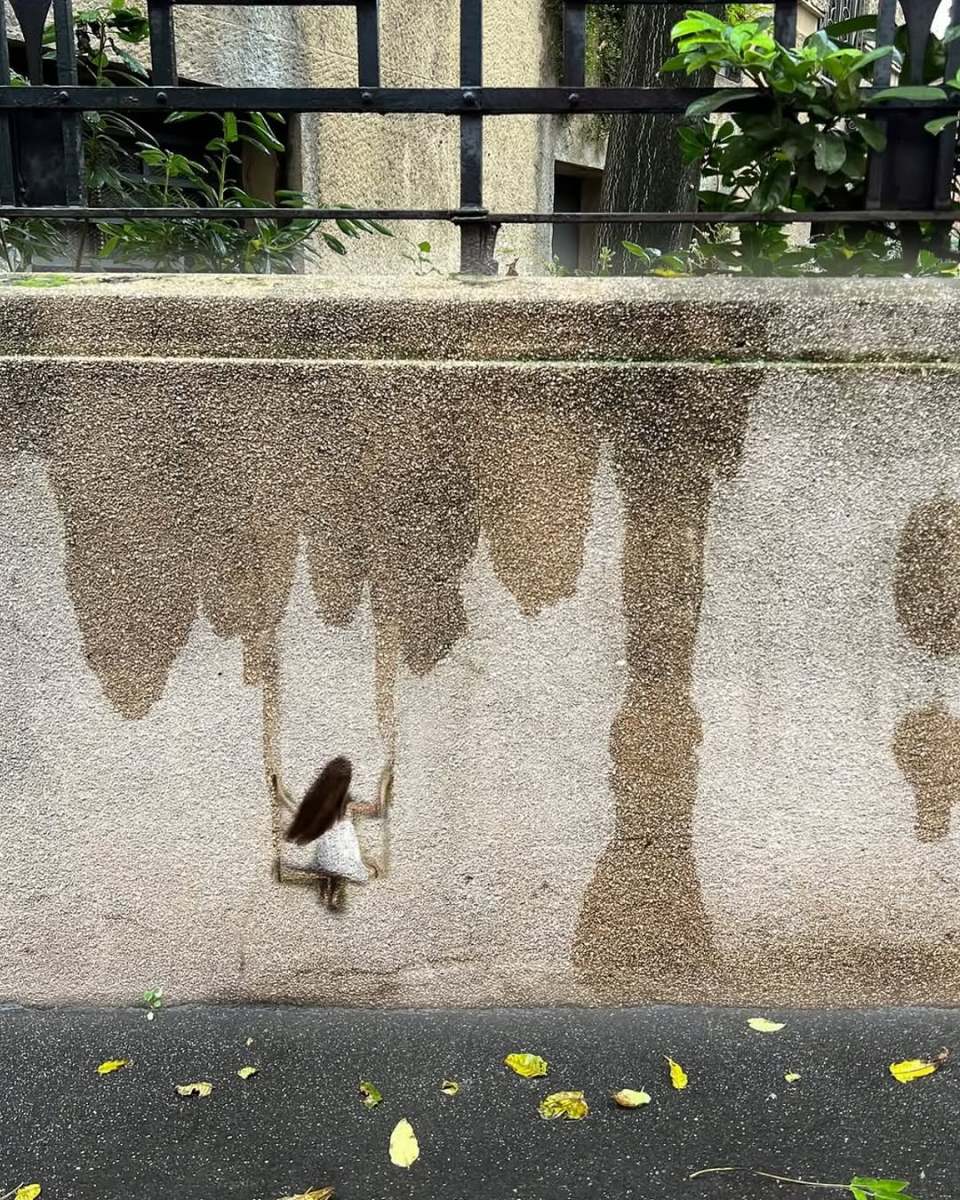Rain Swing by Golsa Golchini in Milan, Italy, showing a tiny painted girl using two water stains as swing ropes on a concrete wall.