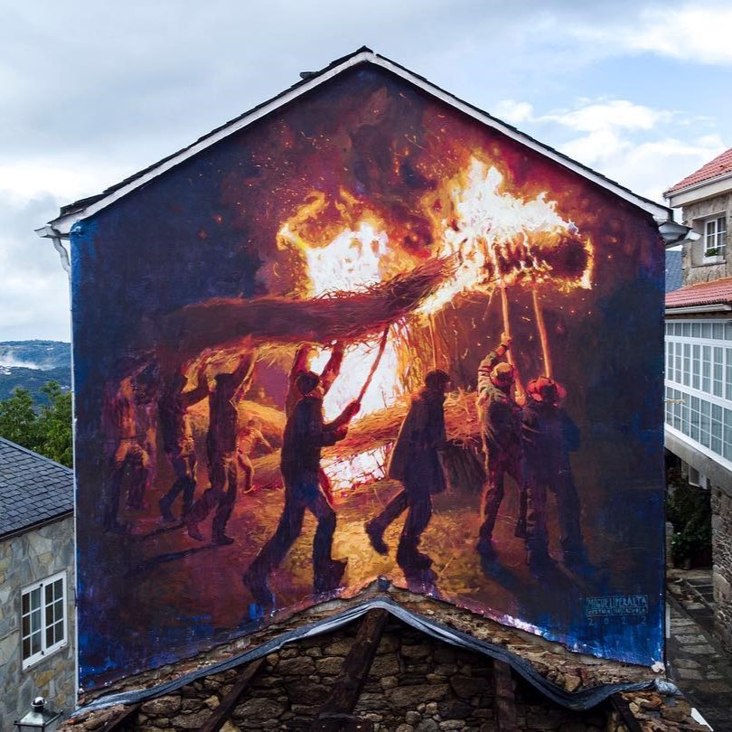 Miguel Peralta mural in Castro Caldelas, Spain, showing figures carrying flaming bundles in a nighttime procession that symbolizes the end of winter and the arrival of spring.