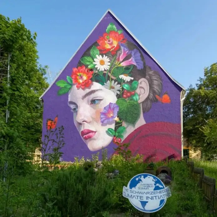 Natalia Rak mural in Austria showing a young woman's profile with flowers and leaves woven through her face and hair.