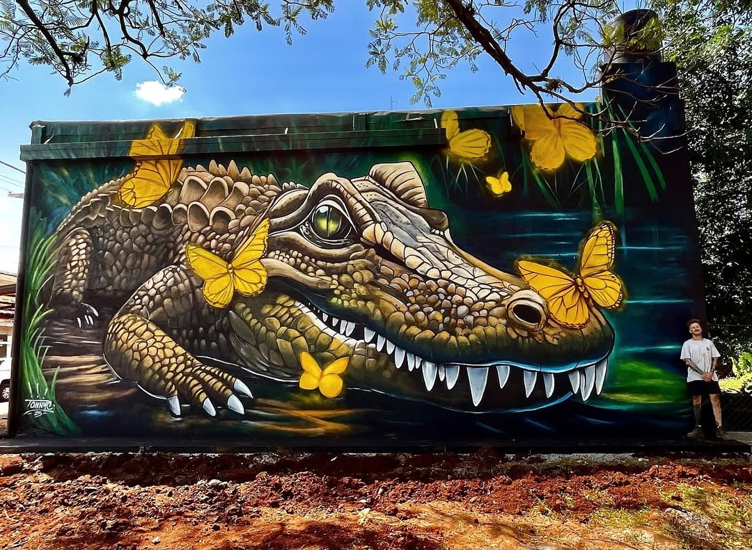 Yacaré by Tonnyc in Argentina shows a caiman surrounded by bright yellow butterflies over dark green water.