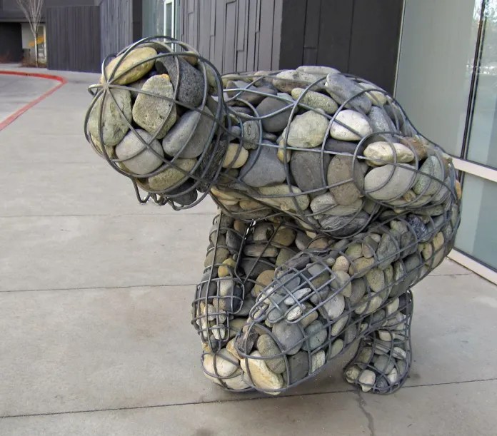 Powerful emotional sculpture by Celeste Roberge titled The Weight of Grief, featuring a steel human figure filled with stones.