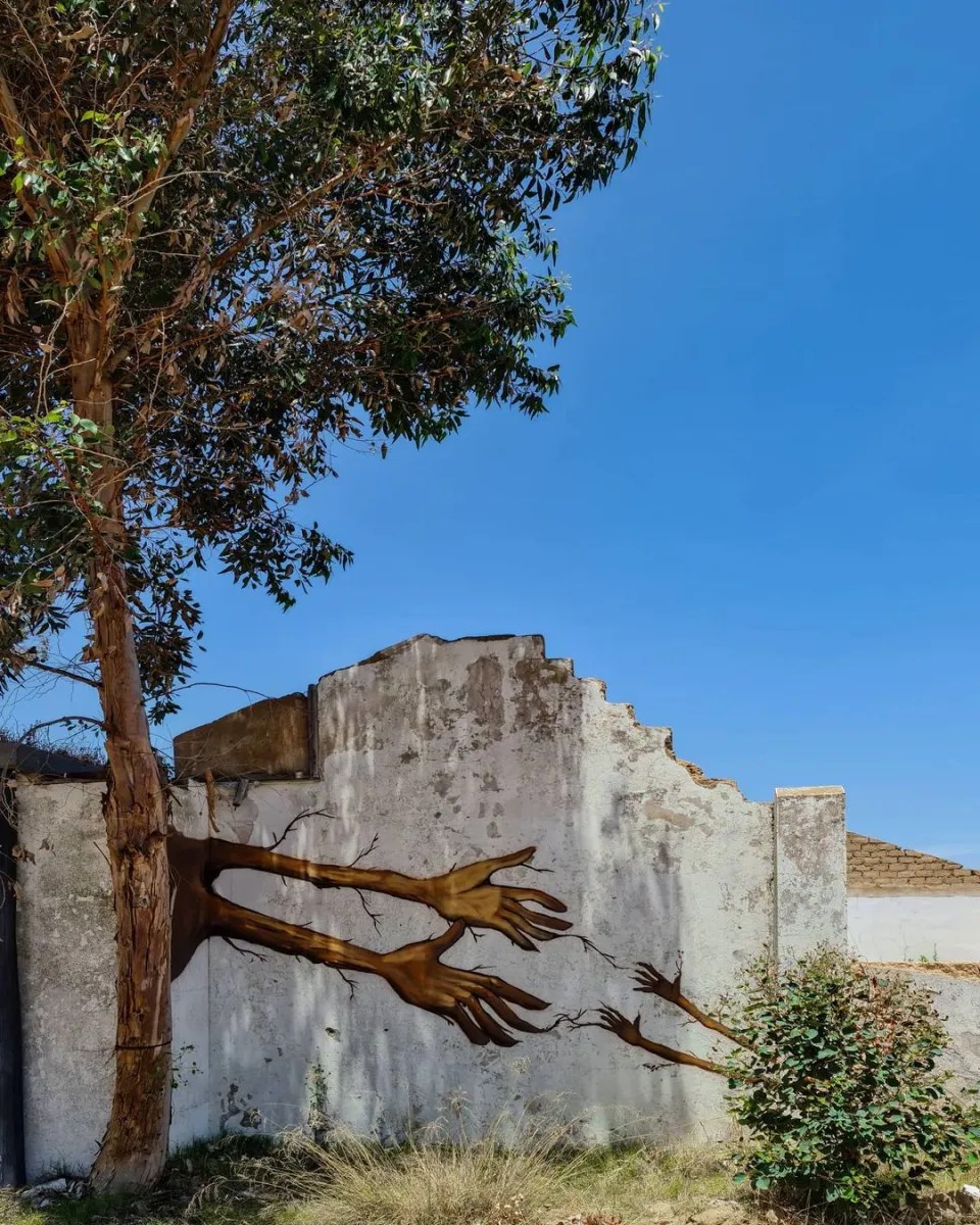Tender street art mural by Falko One in South Africa, titled Family Tree, where a real tree trunk is integrated into the mural.