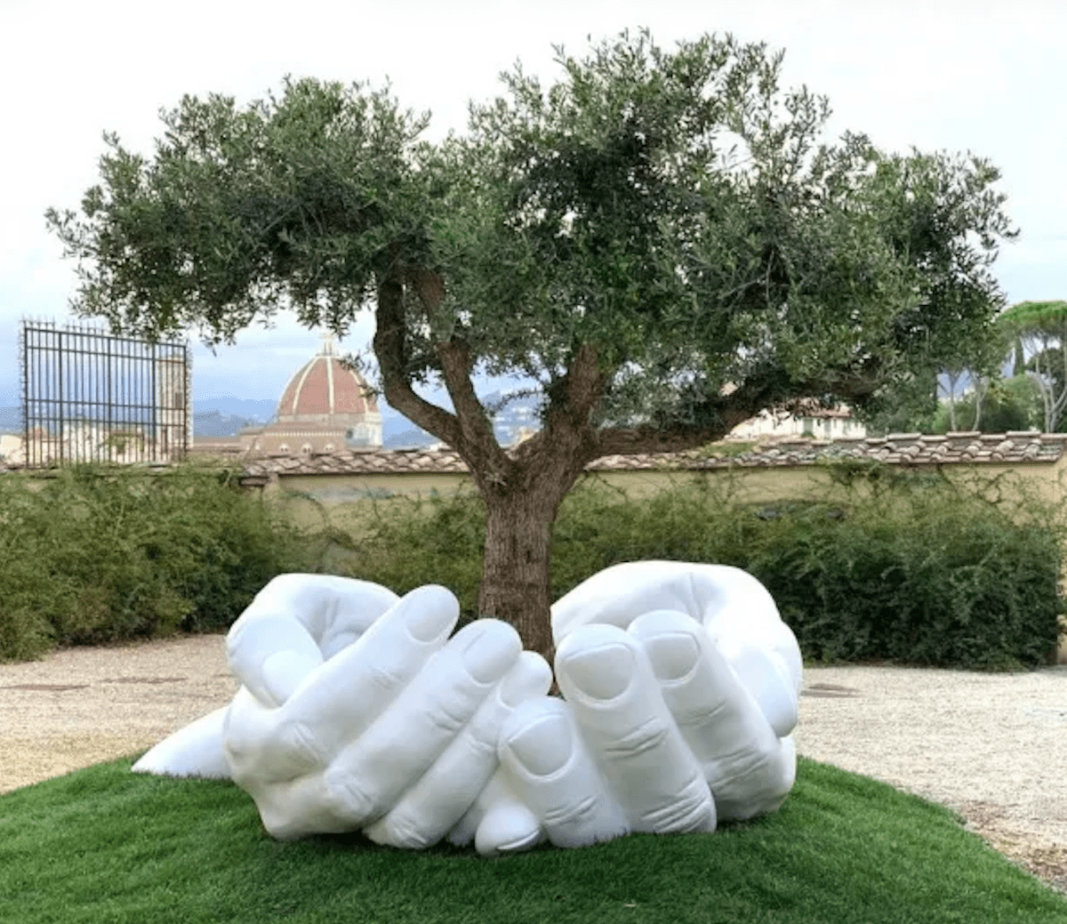 Powerful sculpture Give by Lorenzo Quinn at The Uffizi Gardens in Florence, Italy, featuring giant hands cradling a living tree.