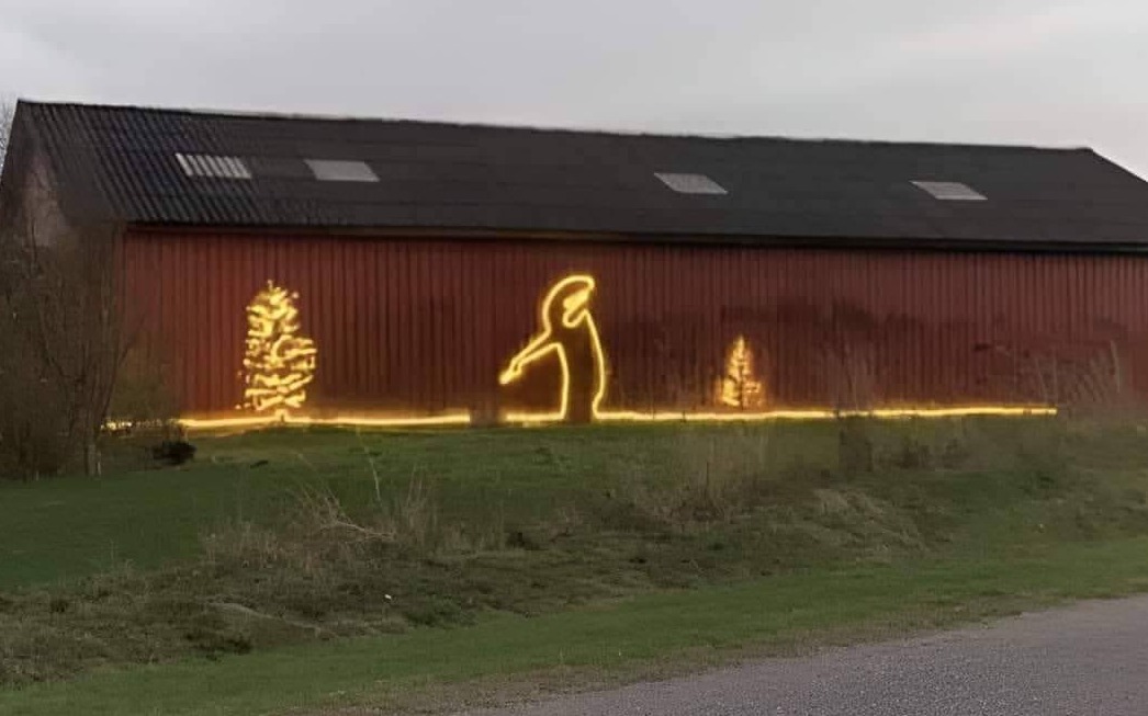 Minimalist street art mural of the character La Linea painted across a barn wall.