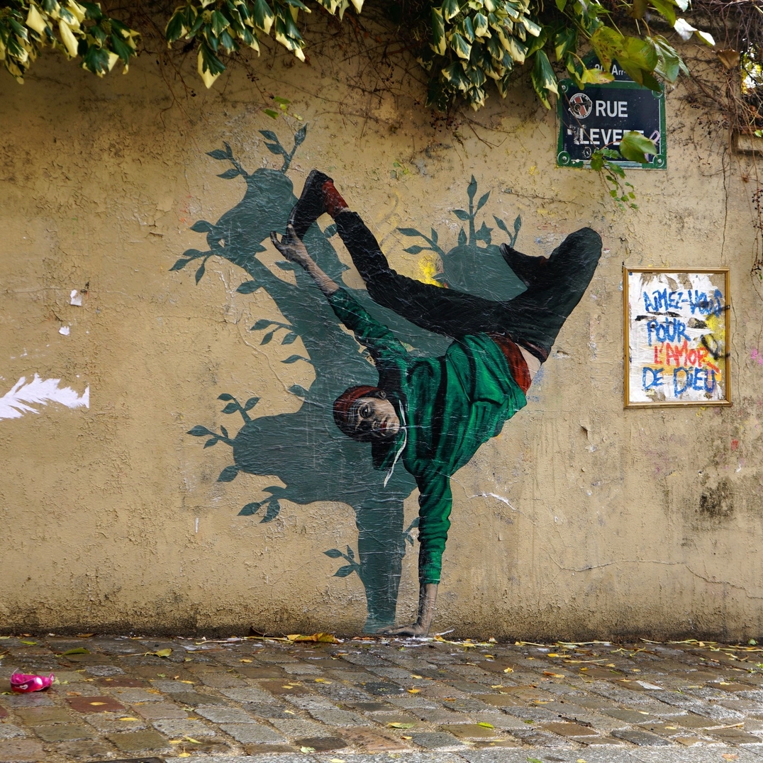 Clever and funny street art installation by Levalet in Paris, France, titled Planté là, where a mural figure is interacting with real street foliage.