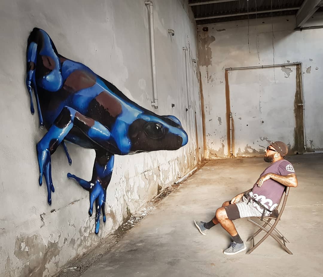Vibrant and realistic 3D street art mural of a giant blue frog by Odeith in Portugal.