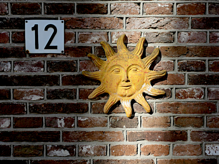 Foto van reliëf aan muur met afbeelding van zon met gezicht