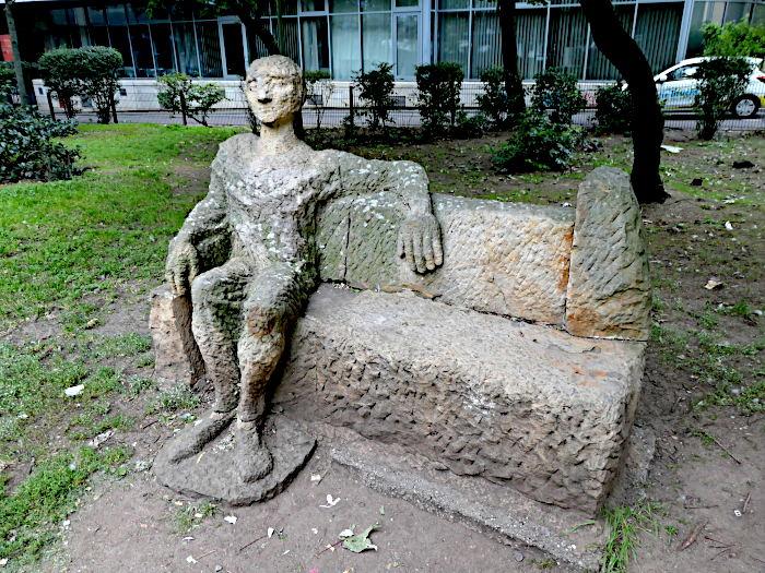 Foto van beeld van bank met zittende figuur met arm nonchalant over de rugleuning