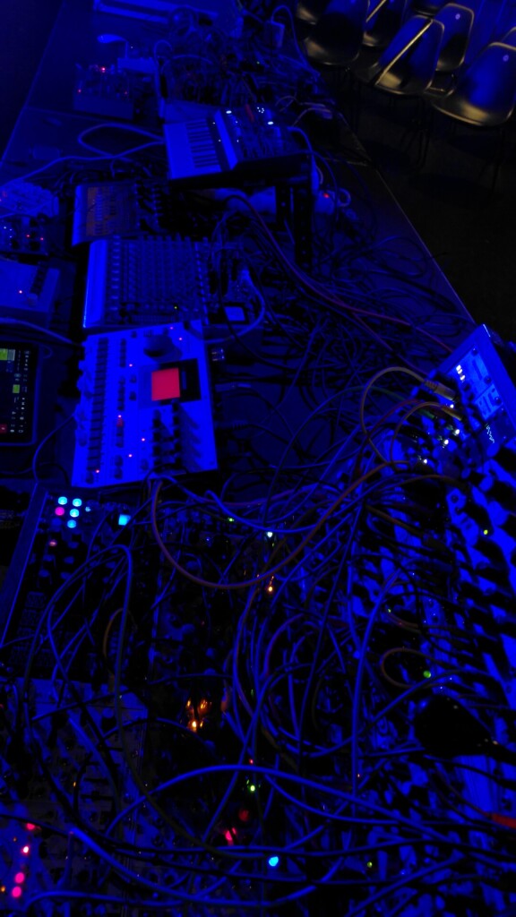 dark blueish photo of modular synths and other equipment 