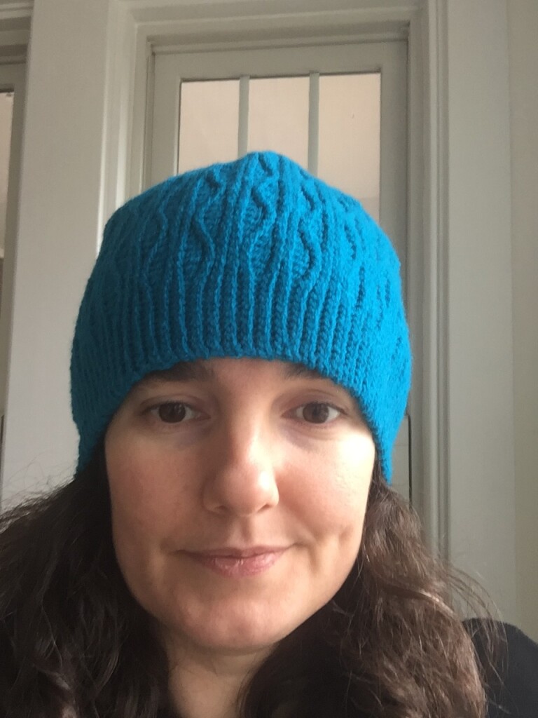 Me wearing a crochet beanie. The beanie is turquoise with alternating straight and wavy ribs.