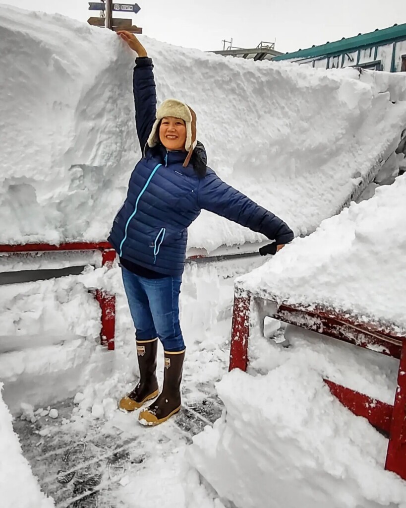 165 centimeter person stands next to snow pile much taller than her