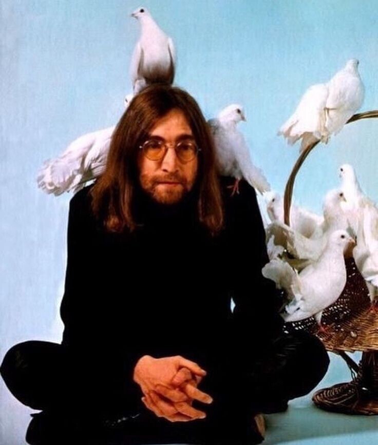 John Lennon sitting cross-legged and surrounded by doves