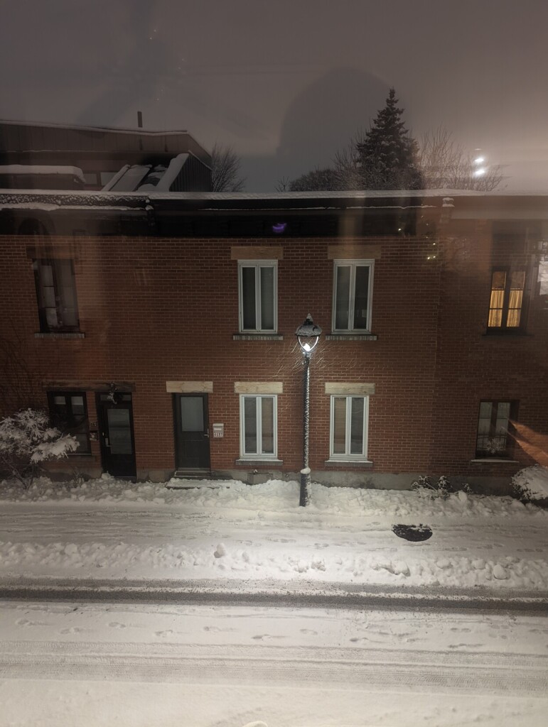 Brick city houses, street lamp, snow piling on the street and sidewalks