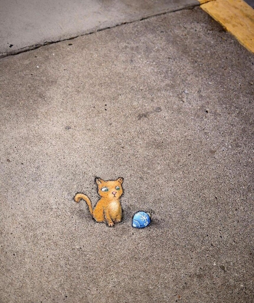 Streetart. Chalkart on the Sidewalk. Small cat with a Christmas tree ball.