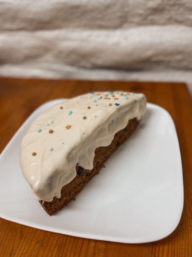 A half of a carrot cake with drippy cream cheese icing