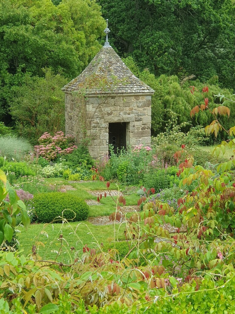 small weathered stone tower in alot of different plants.