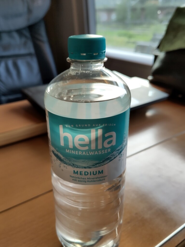 A bottle of water on an ICE train table. The label says "hella".