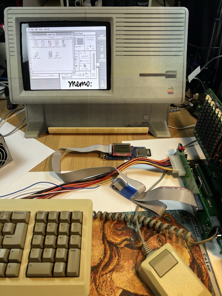 Vintage computer with a keyboard and mouse in the foreground, and various electronic components and cables visible around it.