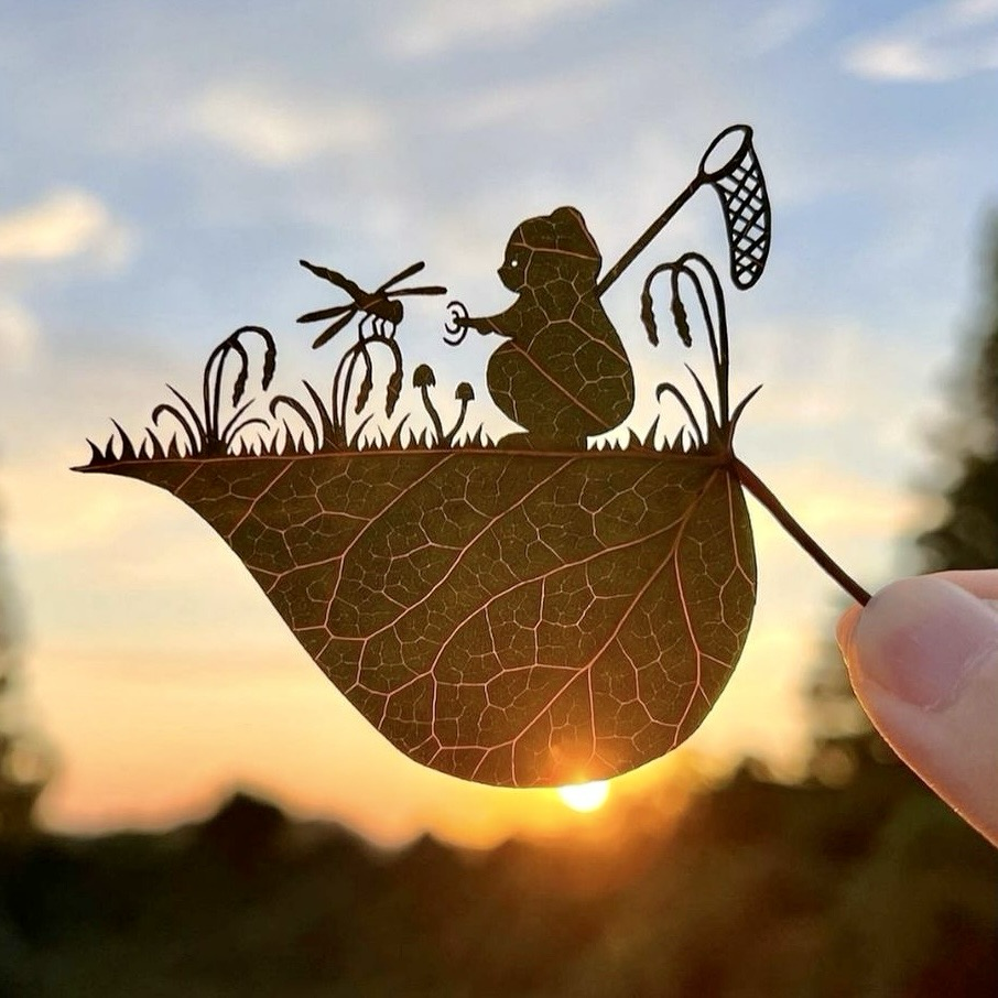 Cut-out leave with an animal carrying a net over its shoulder & a dragonfly in front which it attracts with some grass.