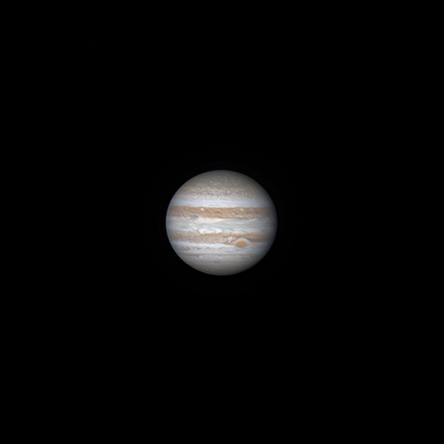 Colour image of Jupiter, a beige sphere with horizontal brown bands. The bottom band is interrupted by the great red spot, a centuries-old storm that looks like a little oval. The beige band in the middle has blueish gray waves. 