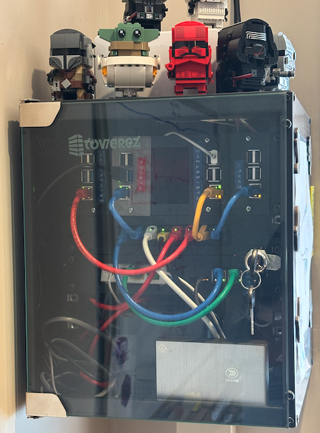 A small SOHO 10" rack mounted on the wall, with network cables and Raspberry Pis visible inside, and a collection of Lego Star Wars Brickheadz sitting on top.