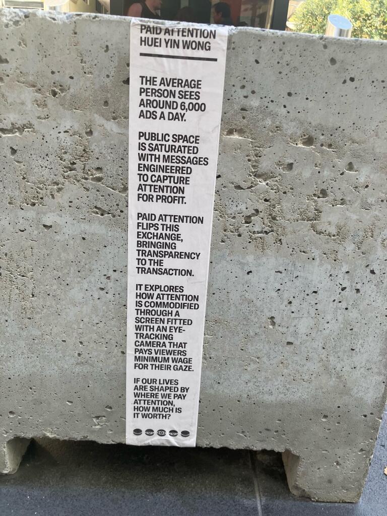 A label that says paid attention HUEI YIN WONG
THE AVERAGE PERSON SEES AROUND 6,000
ADS A DAY.
PUBLIC SPACE IS SATURATED WITH MESSAGES ENGINEERED TO CAPTURE ATTENTION FOR PROFIT.
PAID ATTENTION FLIPS THIS EXCHANGE, BRINGING TRANSPARENCY TO THE
TRANSACTION.
IT EXPLORES HOW ATTENTION IS COMMODIFIED
THROUGH A SCREEN FITTED
WITH AN EYE-TRACKING
CAMERA THAT PAYS VIEWERS
MINIMUM WAGE FOR THEIR GAZE.
IF OUR LIVES ARE SHAPED BY WHERE WE PAY ATTENTION, HOW MUCH IS IT WORTH?