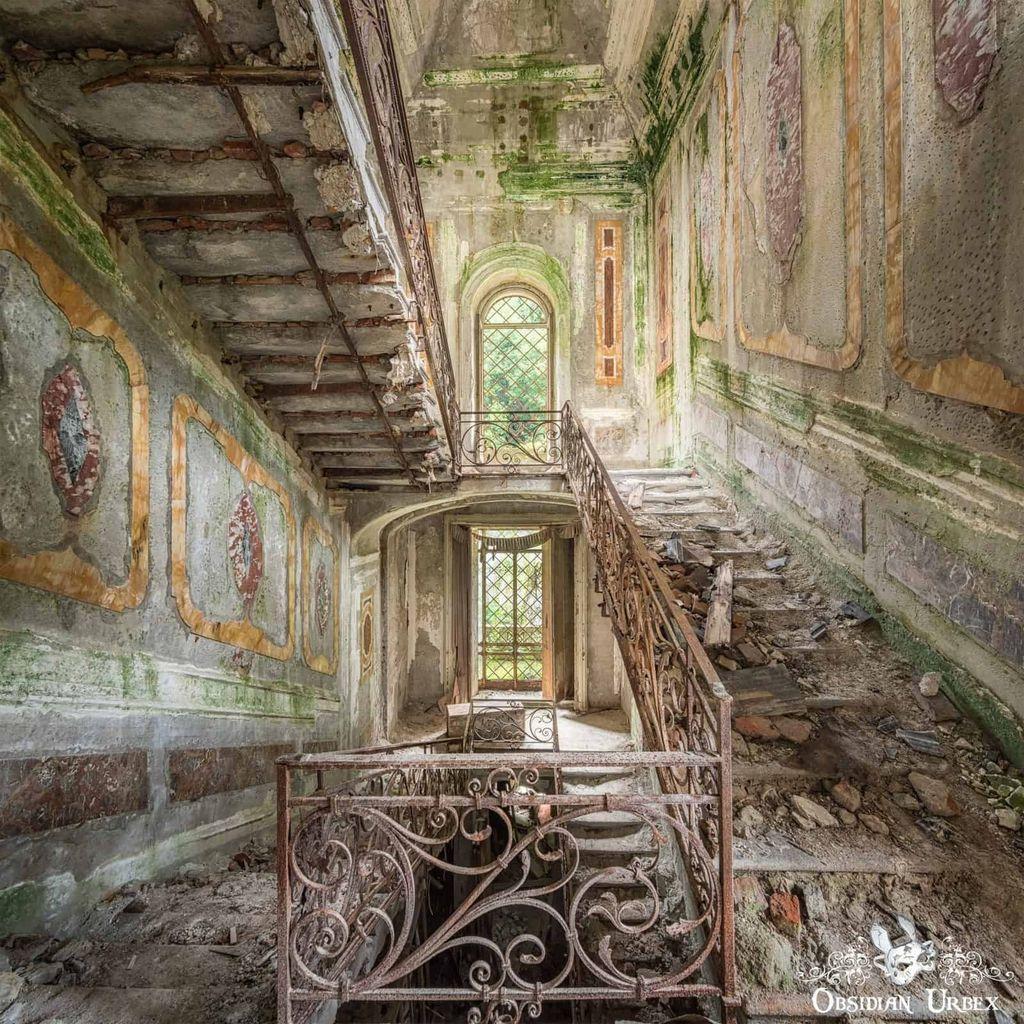 Grand but decaying staircase inside an old mansion